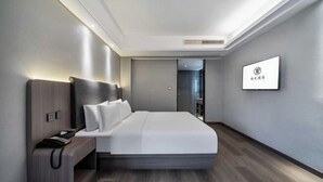 Una habitación de hotel moderna con una cama grande, una mesita de noche y un televisor de pantalla plana montado en la pared.
