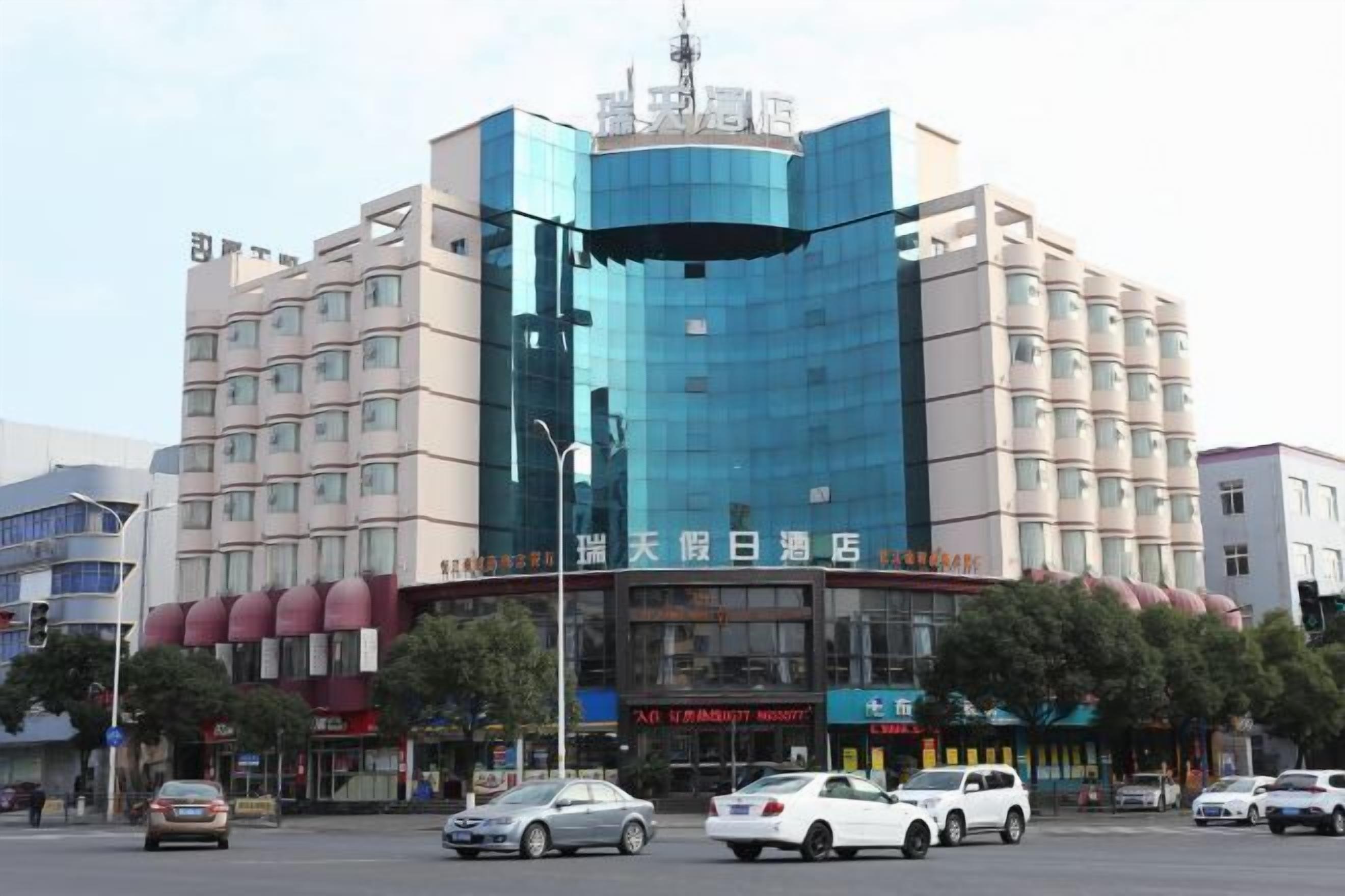 Un hotel de varios pisos con una fachada moderna, que presenta una amplia sección de vidrio y una serie de balcones.