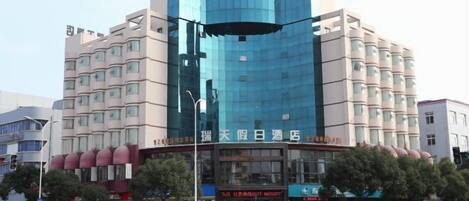Un hotel de varios pisos con una fachada moderna, que presenta una amplia sección de vidrio y una serie de balcones.