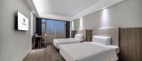 A hotel room with two beds, a desk, a chair, and a TV on the wall.