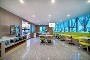 Un restaurante moderno con una barra larga, varias zonas de estar y vistas a la ciudad a través de amplios ventanales.
