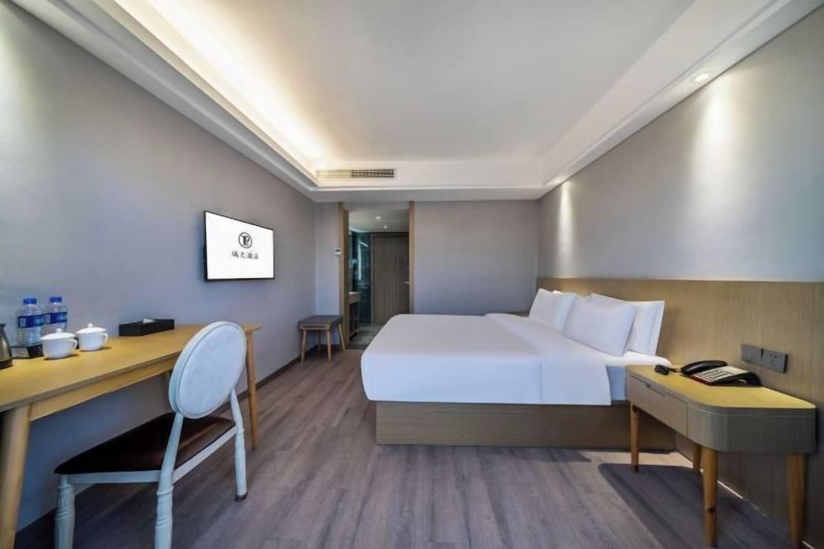 Una habitación de hotel moderna con cama, escritorio, silla y una pequeña mesa con otra silla.