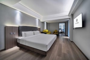 Habitación de hotel moderna con una cama grande, un televisor de pantalla plana y vista al pasillo.