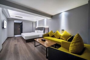 Una habitación de hotel moderna con cama, sofá, mesa de centro y escritorio.