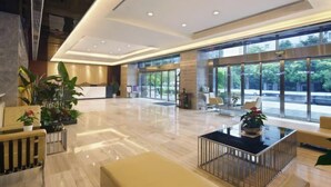 Un vestíbul ampli amb una recepció, zones d'estar i grans finestres que ofereixen vistes cap a l'exterior.