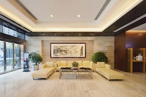 A modern lobby with a large sectional sofa, a coffee table, and a large abstract painting on the wall. - Three Gorges Serviced Apartments (Chengdu)
