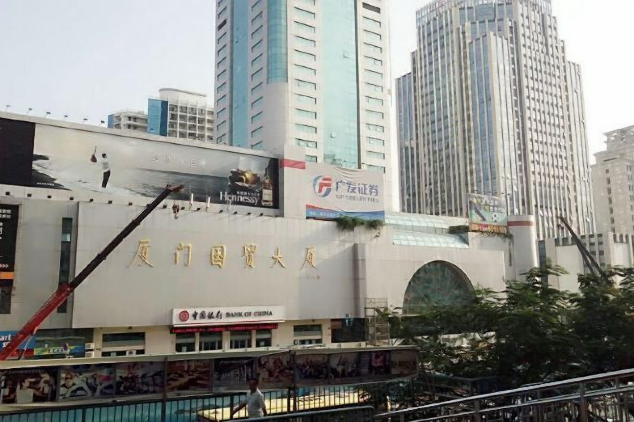 A building with a large sign in a foreign language, a crane, and a billboard.