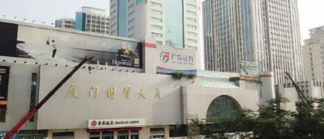 A building with a large sign in a foreign language, a crane, and a billboard.