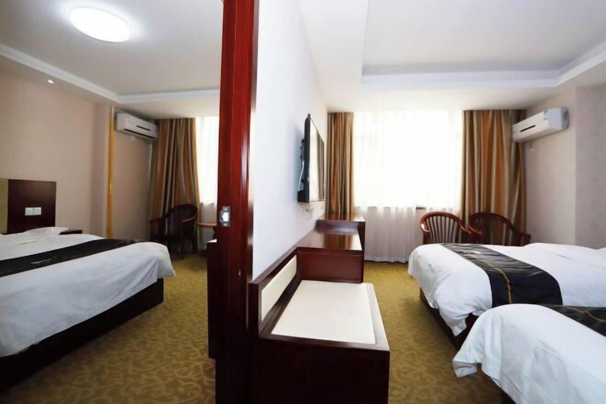 A hotel room with two beds, a desk, a chair, and a TV.