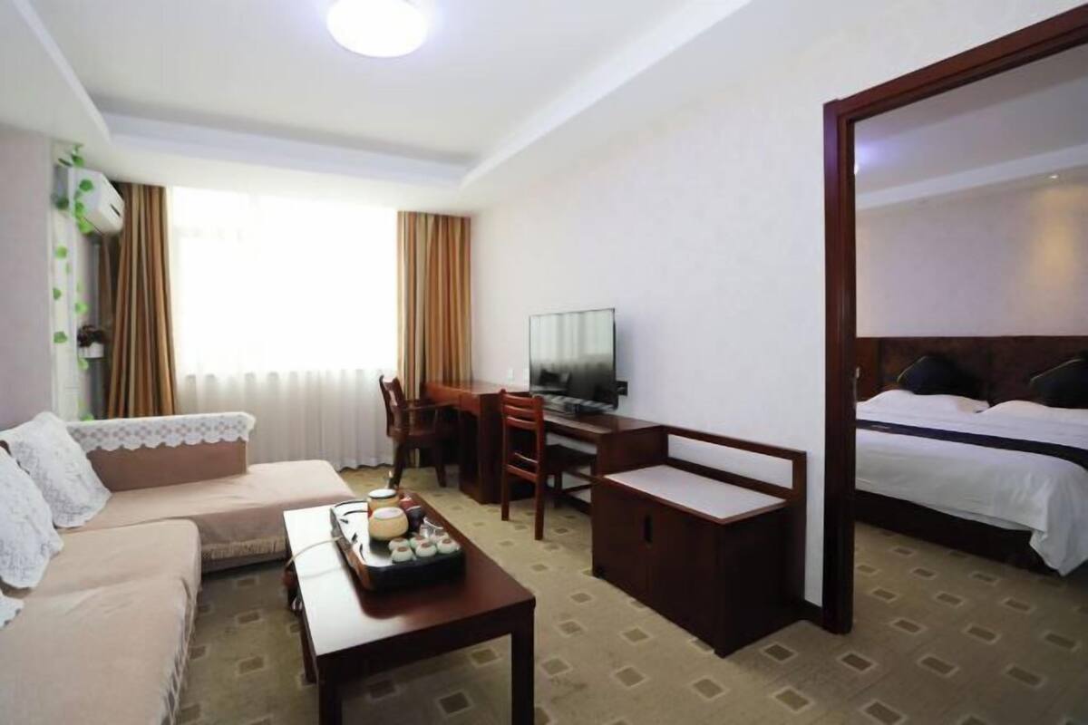 A hotel room with a bed, a desk with a chair, a sofa, and a television.