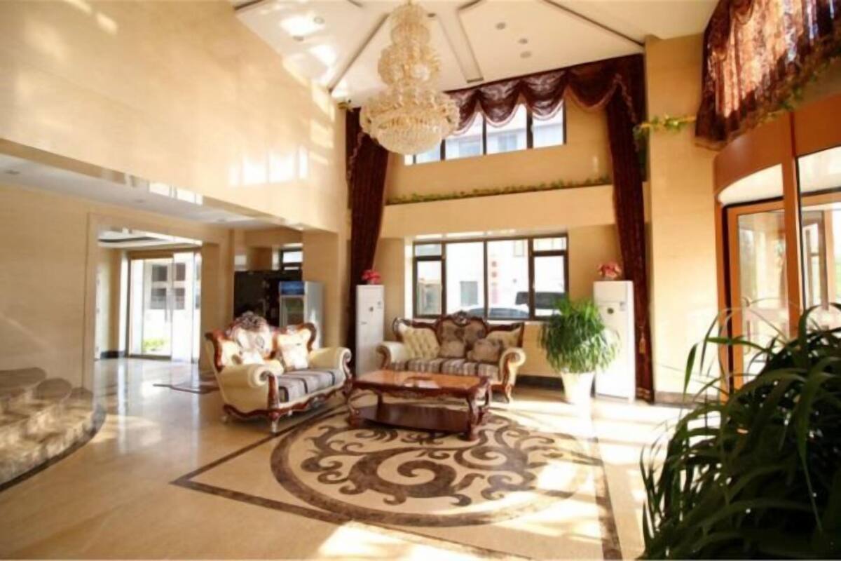 A spacious lobby with a chandelier, a patterned rug, and a sofa.