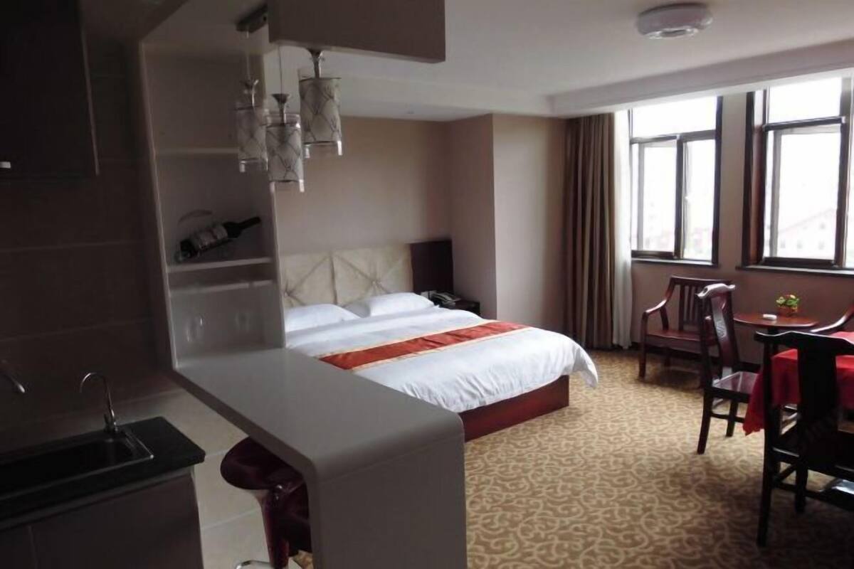 A hotel room with a bed, a desk, a chair, a window, and a minibar.