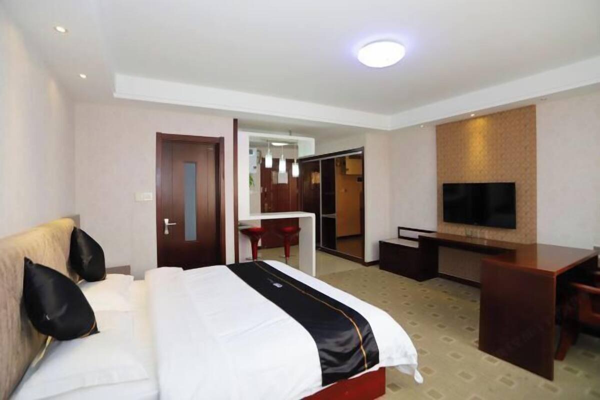A hotel room with a bed, a desk, a television, and a mirror.