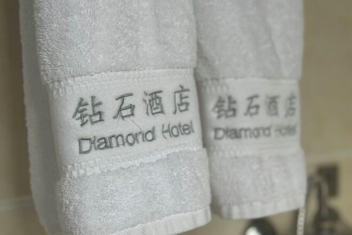A white towel with embroidered text reading "Diamond Hotel."