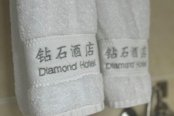 A white towel with embroidered text reading "Diamond Hotel."