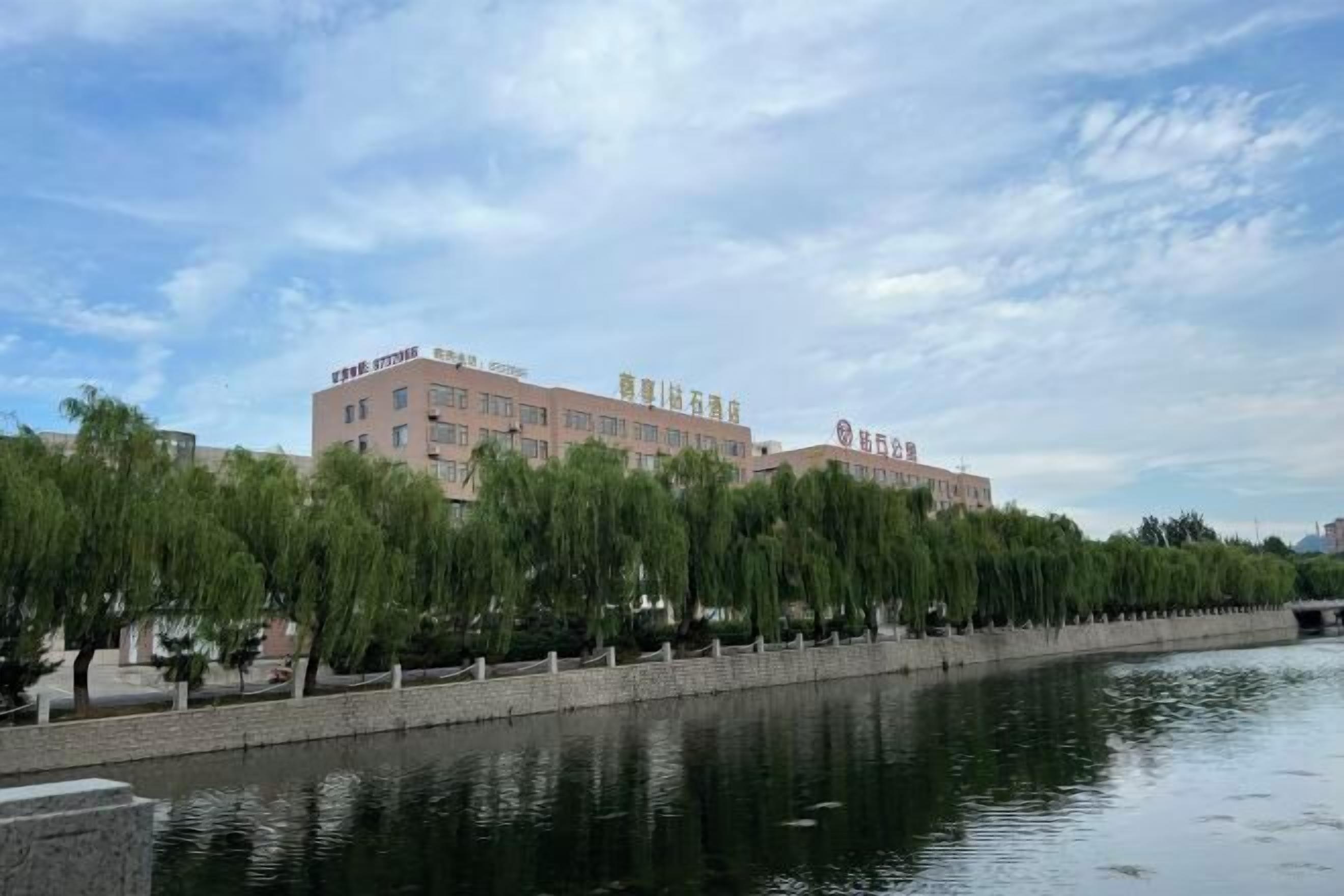 A building with multiple floors and a row of trees in front.