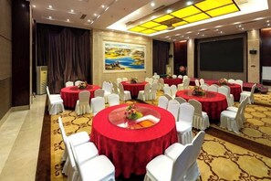 A conference room with multiple round tables, white chairs, and a carpeted floor. - Kunming Southwest Hotel (Kunming)