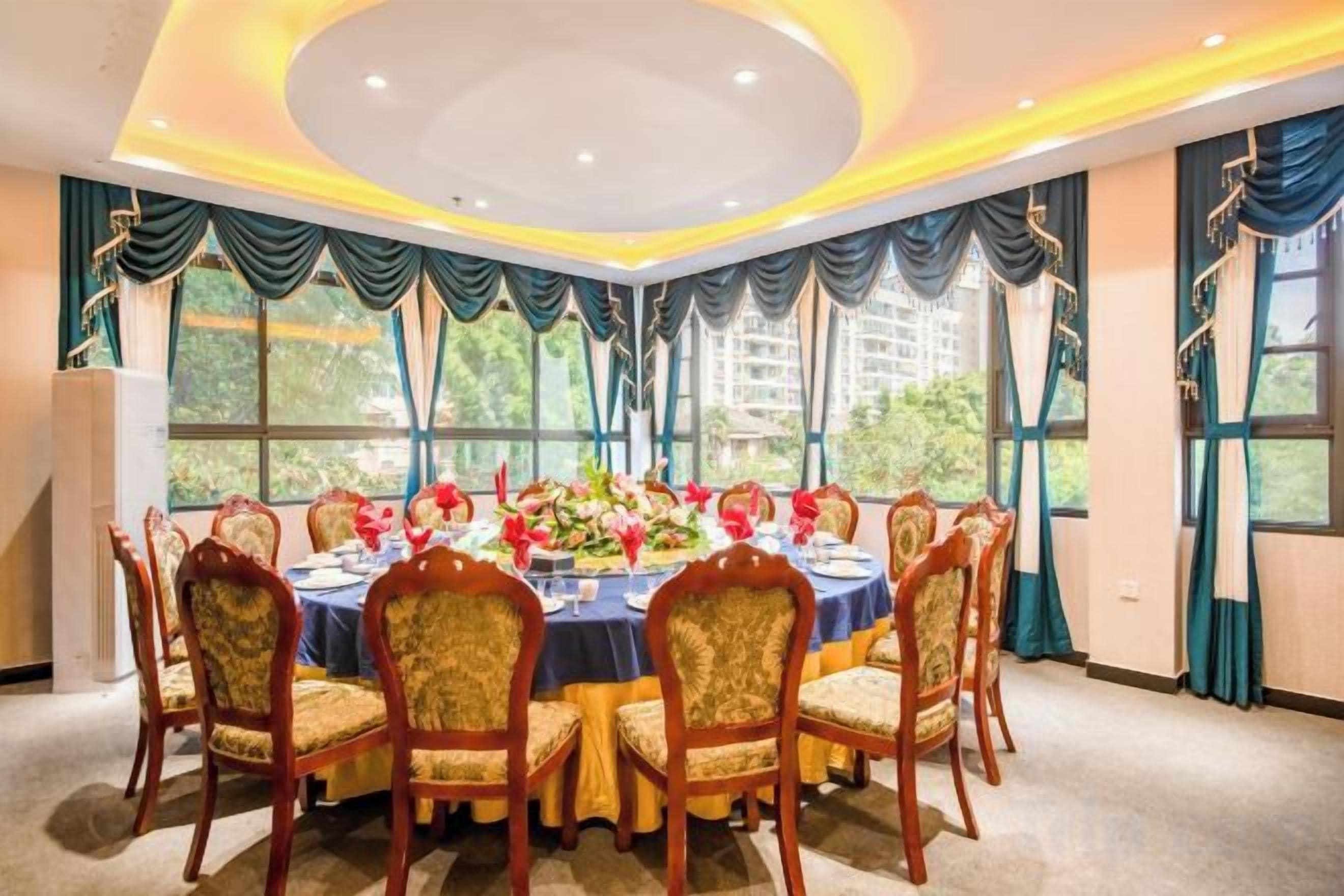 A dining room with a round table, chairs, and a floral centerpiece.