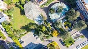 An aerial view of a modern building with a circular water feature, a green lawn, and a parking area. - Kunming Southwest Hotel (Kunming)