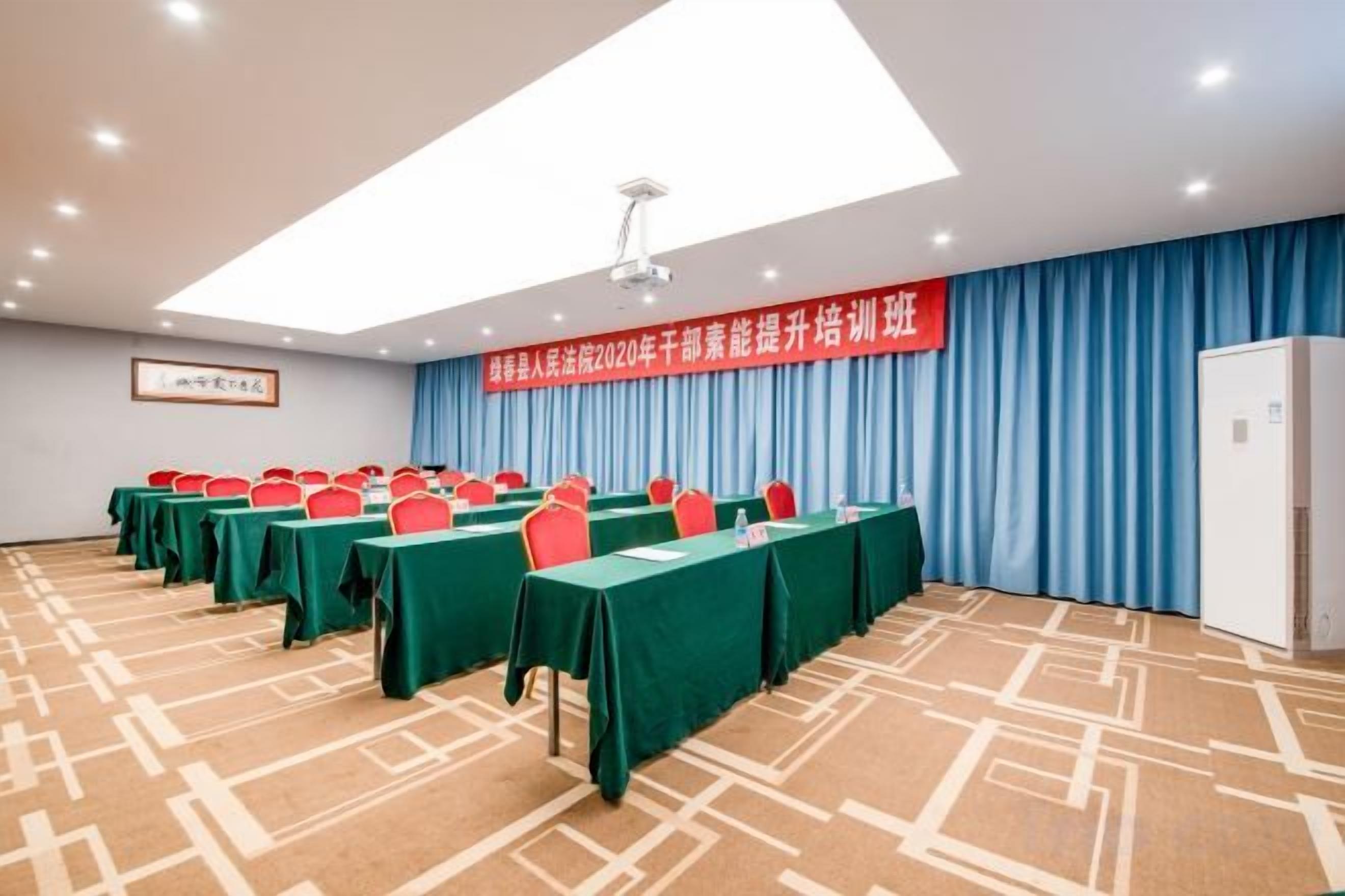 A conference room with tables and chairs, a banner, and a patterned carpet.