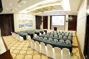 A conference room with rows of tables and chairs, a projector screen, and a carpeted floor. - Kunming Southwest Hotel (Kunming)