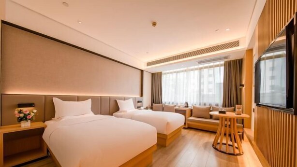 A hotel room with two beds, a sofa, a TV, and a small table. - Kunming Southwest Hotel (Kunming)