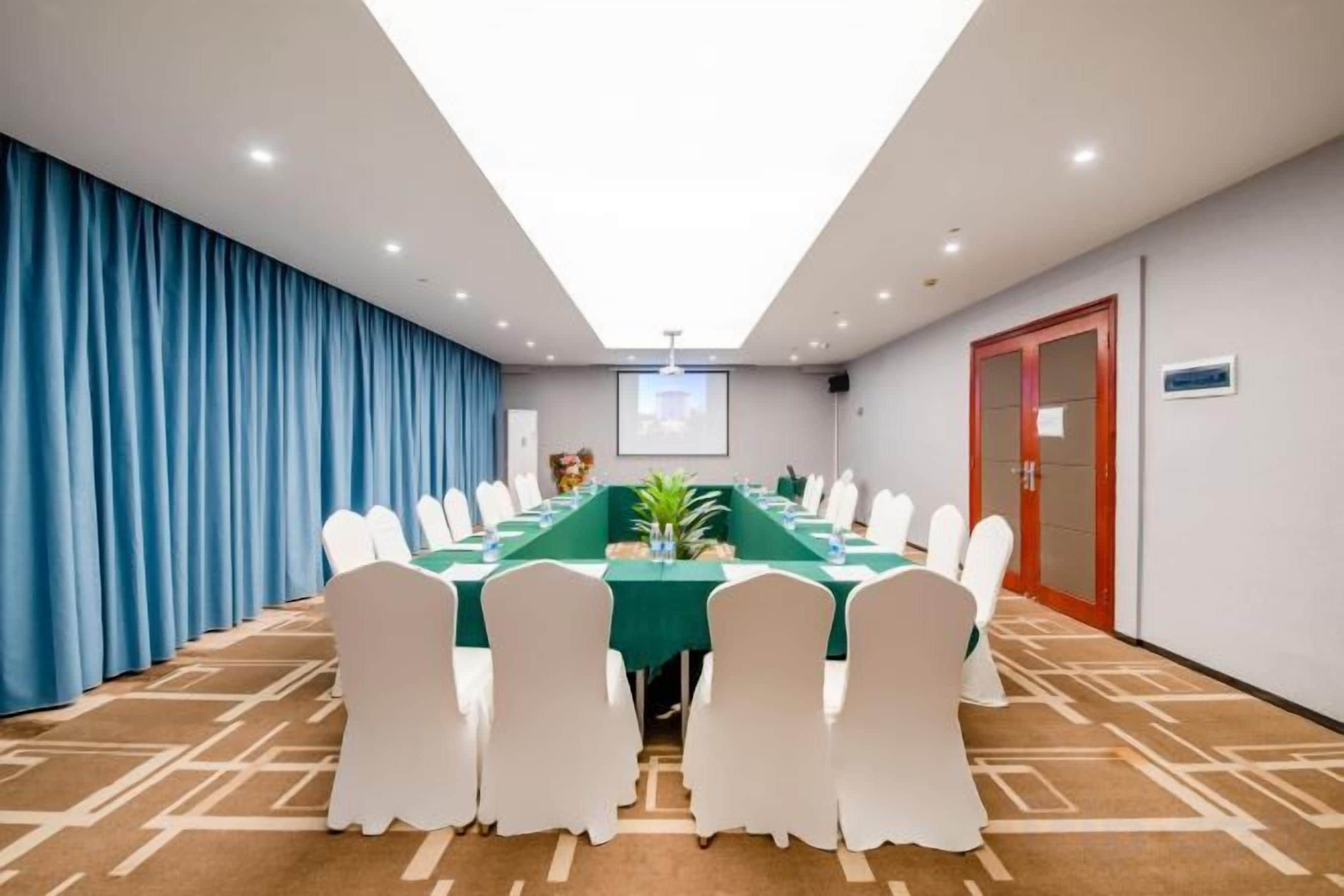 A conference room with a long table, white chairs, and a carpeted floor.
