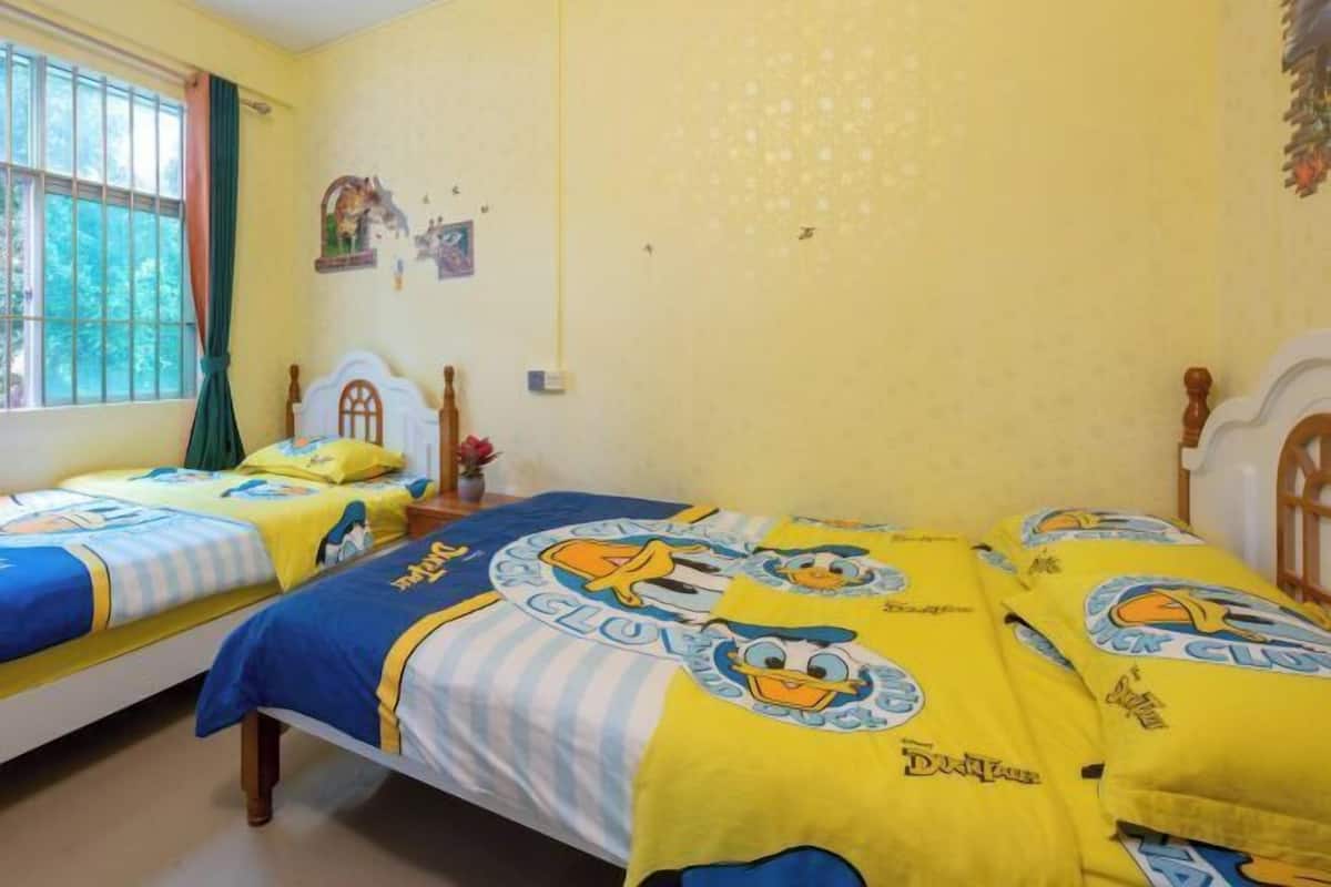A room with two single beds, each with a blue and yellow bedspread featuring cartoon characters.