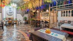 A restaurant with a mosaic floor, tables with fruit, and hanging plants. - HaiBei Hostel (Shenzhen)
