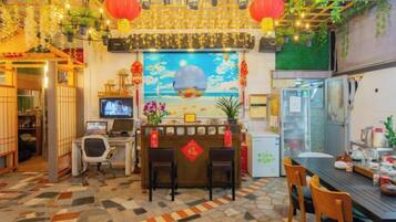 A restaurant with a traditional Asian decor, a counter with stools, and a television screen.