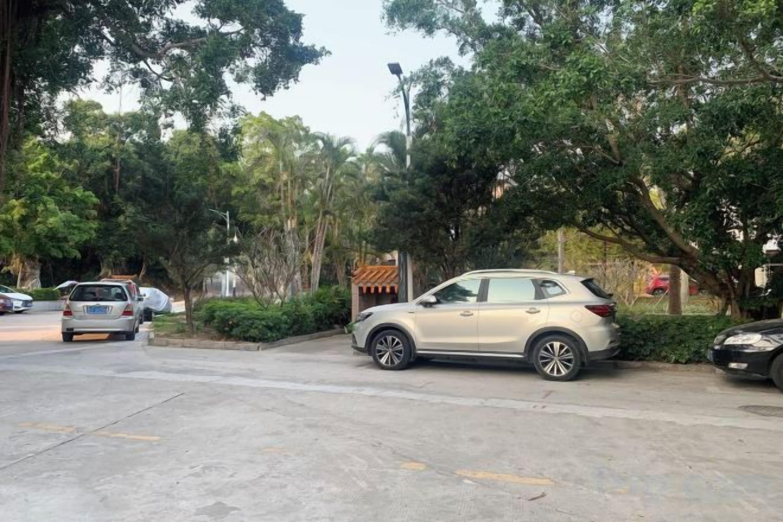 Un estacionamiento con autos, un edificio de techo tradicional y árboles.