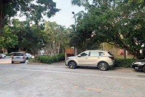 A parking area with cars, a building with a traditional roof, and trees. - HaiBei Hostel (Shenzhen)
