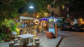 An outdoor dining area with stone tables and chairs, a covered seating area, and a decorative drum. - HaiBei Hostel (Shenzhen)