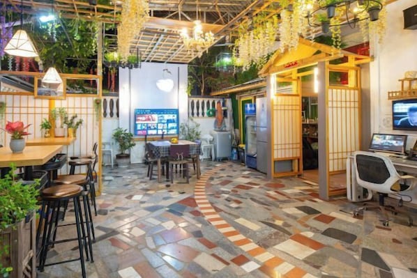 A modern interior with a tiled floor, wooden furniture, and hanging plants. - HaiBei Hostel (Shenzhen)