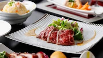 A dining table with various dishes, including a plate with sliced meat and vegetables.