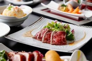 A dining table with various dishes, including a plate with sliced meat and vegetables. - Holiday Inn Resort MIYAZAKI by IHG (Miyazaki City)