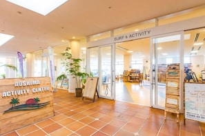 An indoor activity center with a surf and activity shop, a wooden signboard, and a potted plant. - Holiday Inn Resort MIYAZAKI by IHG (Miyazaki City)