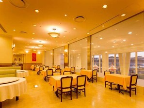 Comedor de hotel con mesas, sillas, ventanas amplias y vistas.
