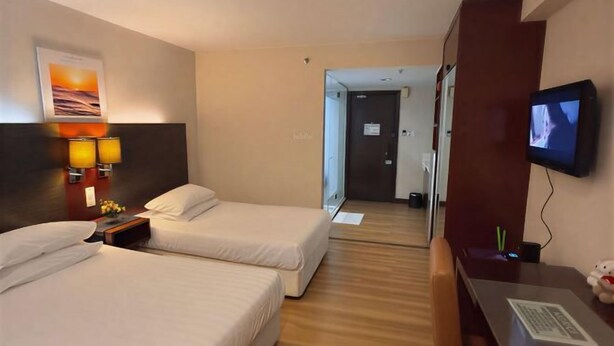 Une chambre d’hôtel avec deux lits, un bureau avec une télévision et un miroir.