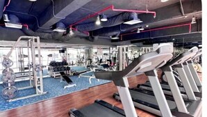 Une salle de sport équipée de tapis de course, d’appareils de musculation et dotée d’un sol recouvert d’une moquette bleue.