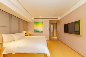 A hotel room with a bed, a TV, a painting, and a hallway leading to another room. - HanTing Hotel (Shanghai Daning Music Plaza Xindian) (Shanghai)