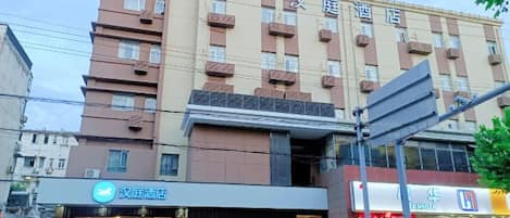 A multi-story hotel with a modern facade, balconies, and a ground-level storefront.