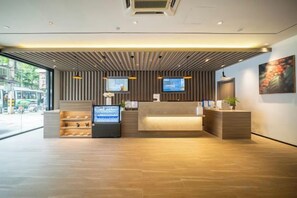 A modern reception area with a wooden reception desk, a television, and a plant. - HanTing Hotel (Shanghai Daning Music Plaza Xindian) (Shanghai)