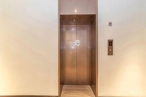 An elevator with a control panel and emergency exit sign. - HanTing Hotel (Shanghai Daning Music Plaza Xindian) (Shanghai)