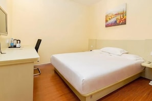 Una habitación de hotel con cama, escritorio, silla y un cuadro en la pared.
