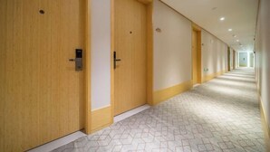 Ein Hotelgang mit Holztüren, Fliesenboden und langer Strecke.