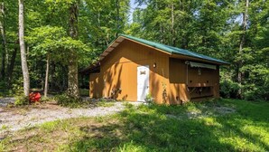 A small wooden cabin with a green roof, surrounded by trees. - Perrywinkle's Retreat-Hidden Paradise Farms (Clarkrange)