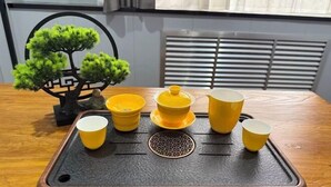 A table with a tray holding yellow cups and a teapot, a bonsai tree, and a decorative black metal piece. - Homeinn Pebble Hotel (Zhengding Railway Station) (Zhengding)