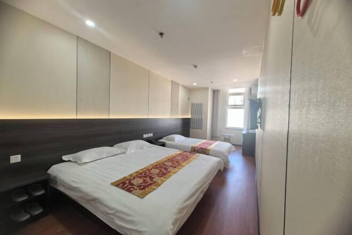 A hotel room with two beds, a wardrobe, and a shoe rack.