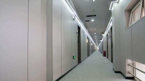 A long, narrow hallway with a tiled floor and walls, lined with doors on one side and a handrail on the other. - Homeinn Pebble Hotel (Zhengding Railway Station) (Zhengding)